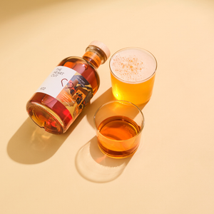 New Riff bourbon bottle lying down with whisky in rocks glass and beer in another glass on beige surface
