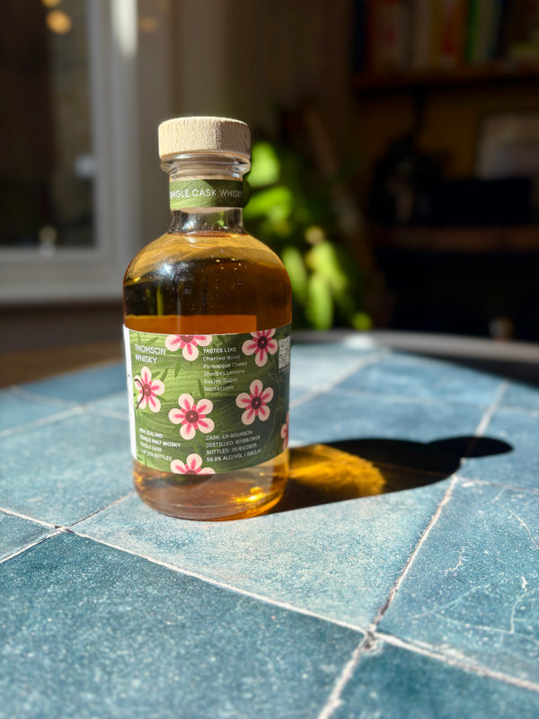 Bottle of whisky with a floral label on a tiled surface

