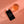 Black bottle labeled 'The Heart Cut' next to a glass of orange liquid on a peach-colored background
