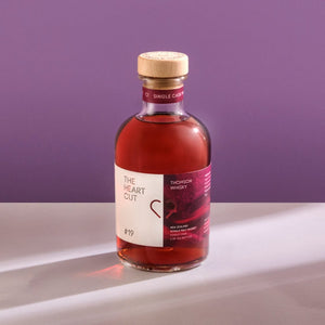 Bottle of The Heart Cut #19 Thomson on a light surface against a purple background