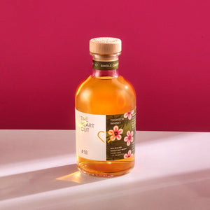 Bottle of The Heart Cut #18 Thomson whisky on a white surface with a red background