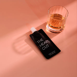 Glass of The Heart Cut whisky next to a Pocket Pour pouch