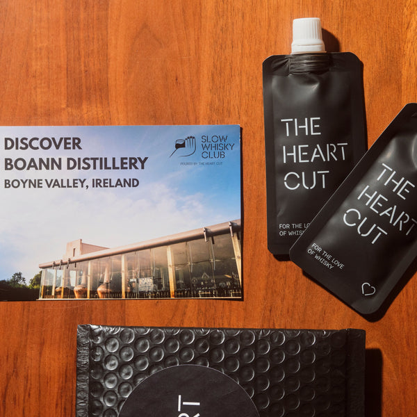 Two black pouches labeled 'The Heart Cut' and a promotional card for Boann Distillery on a wooden surface.